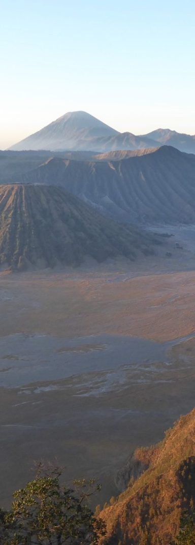 Uitzicht op een berglandschap met vulkanen en valleien bij zonsopgang.