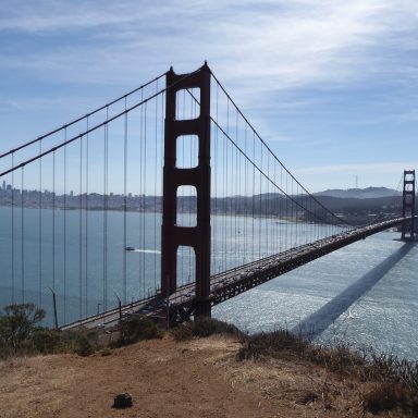 De Golden Gate Bridge met uitzicht op het water en de kustlijn in de achtergrond.