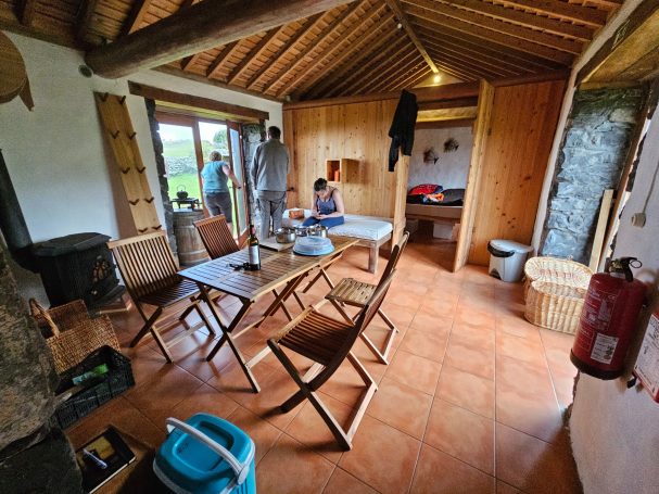 Gezellige woonkamer met houten meubels en een tafel, uitzicht naar buiten, en een open deur.