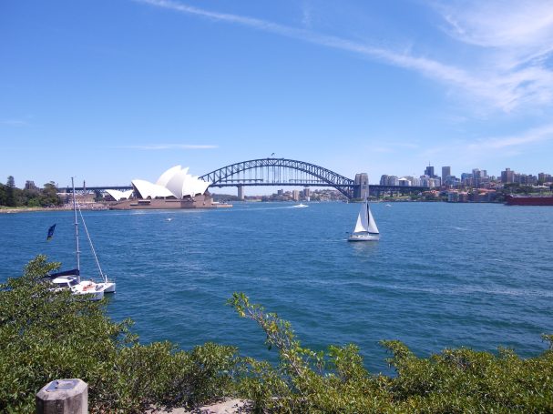 Zicht op de Sydney Harbour Bridge met zeilboot en het Opera House op de achtergrond.