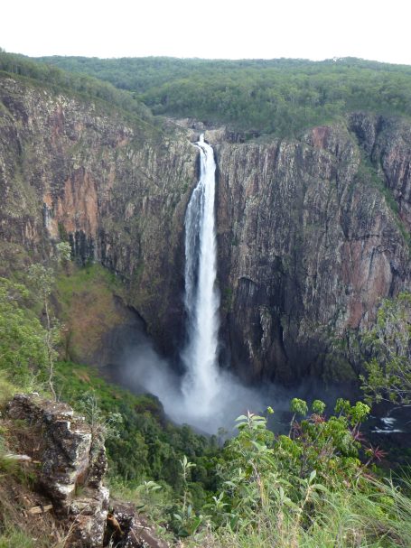 Waterval valt van hoge kliffen omringd door groene vegetatie.