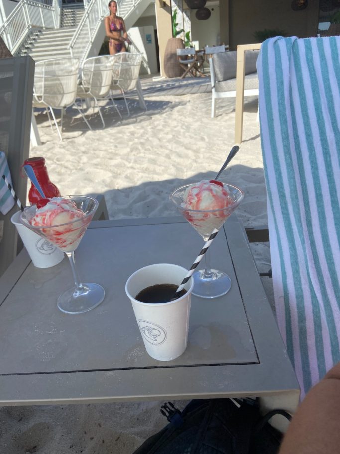 Twee glazen met ijs en een kartonnen bekertje met een rietje op een tafel.