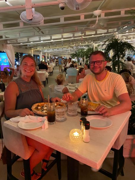 Twee mensen zitten aan een tafel in een restaurant met diners op de achtergrond.